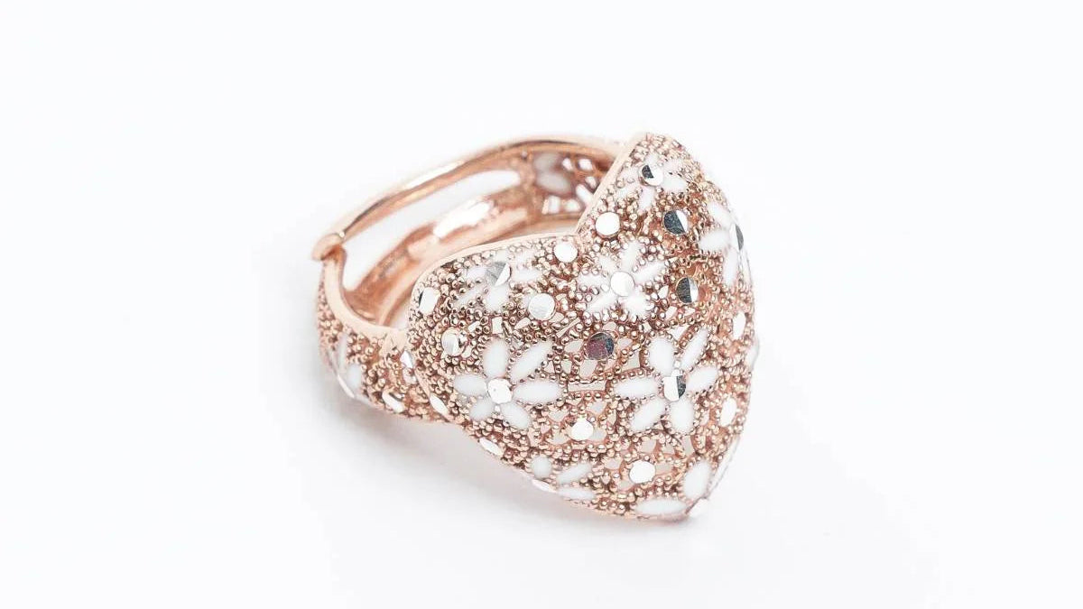 rose gold heart-shaped ring with intricate white floral enamel and bead detailing