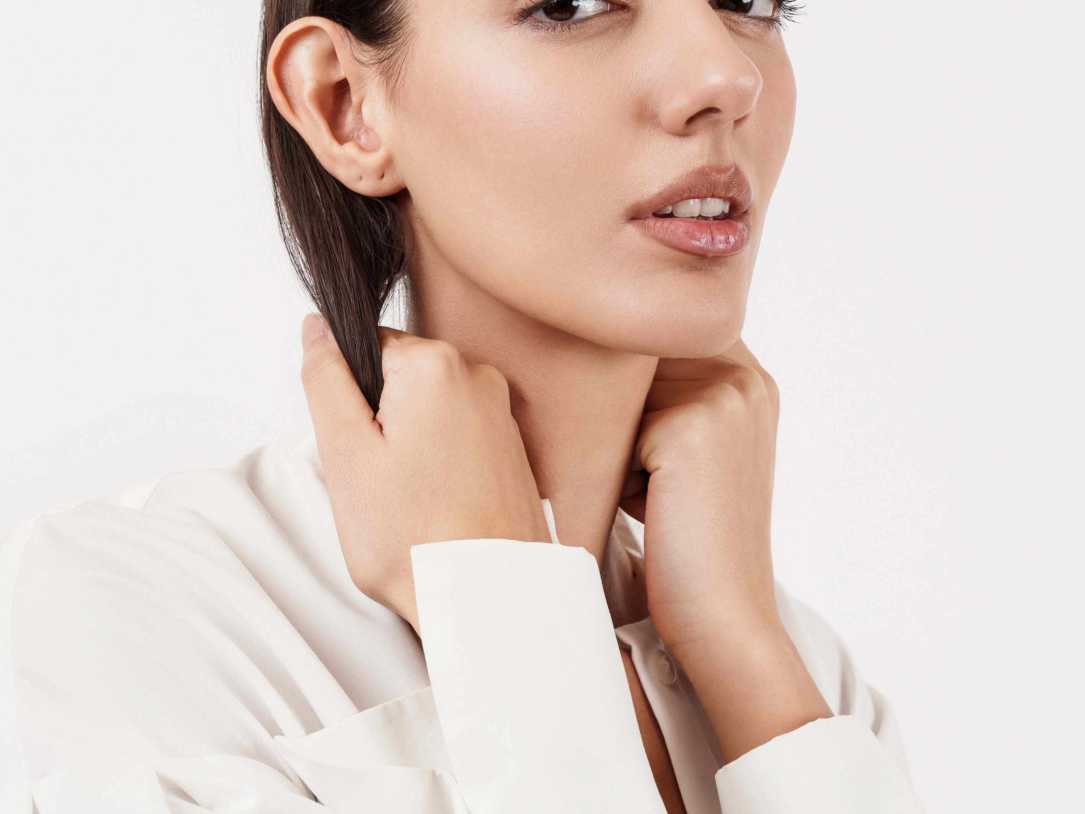 Fashion model in white blouse wearing gold and silver textured bracelets on wrist