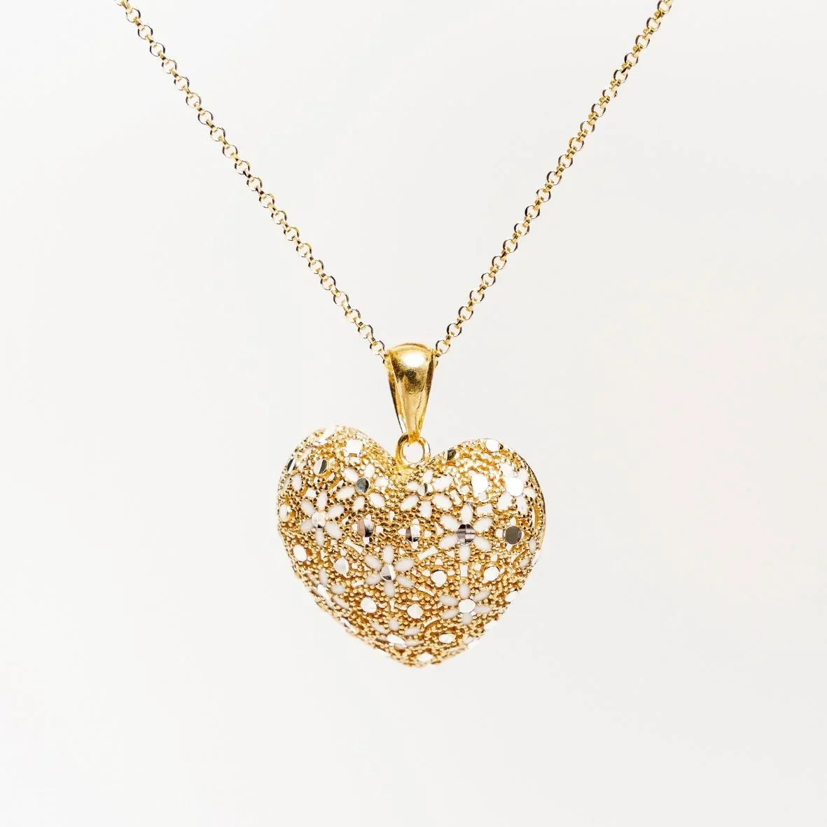 Gold heart pendant necklace with intricate floral filigree design on white background