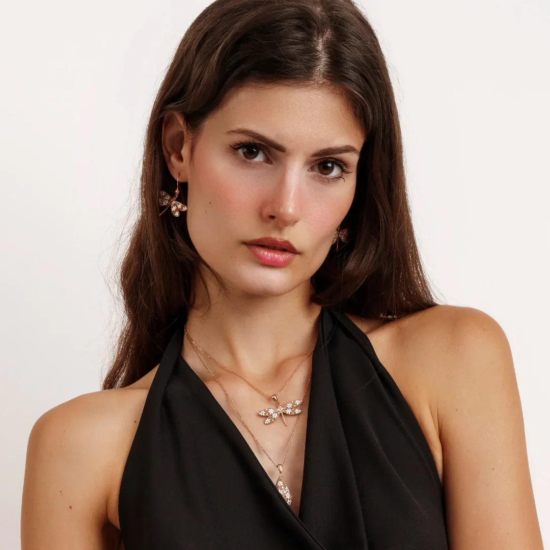 Woman wearing black halter top with gold butterfly earrings and matching layered butterfly necklaces