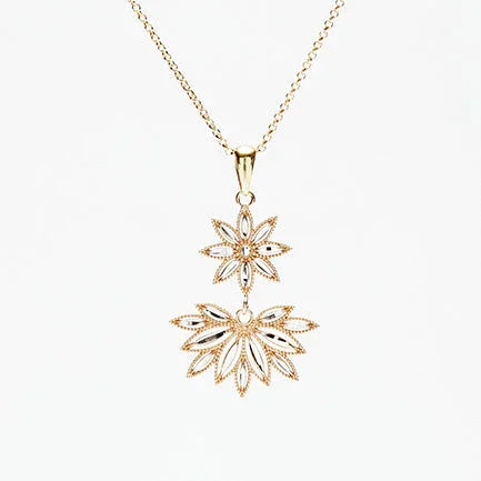 Gold pendant necklace with ornate floral-inspired filigree design on delicate chain