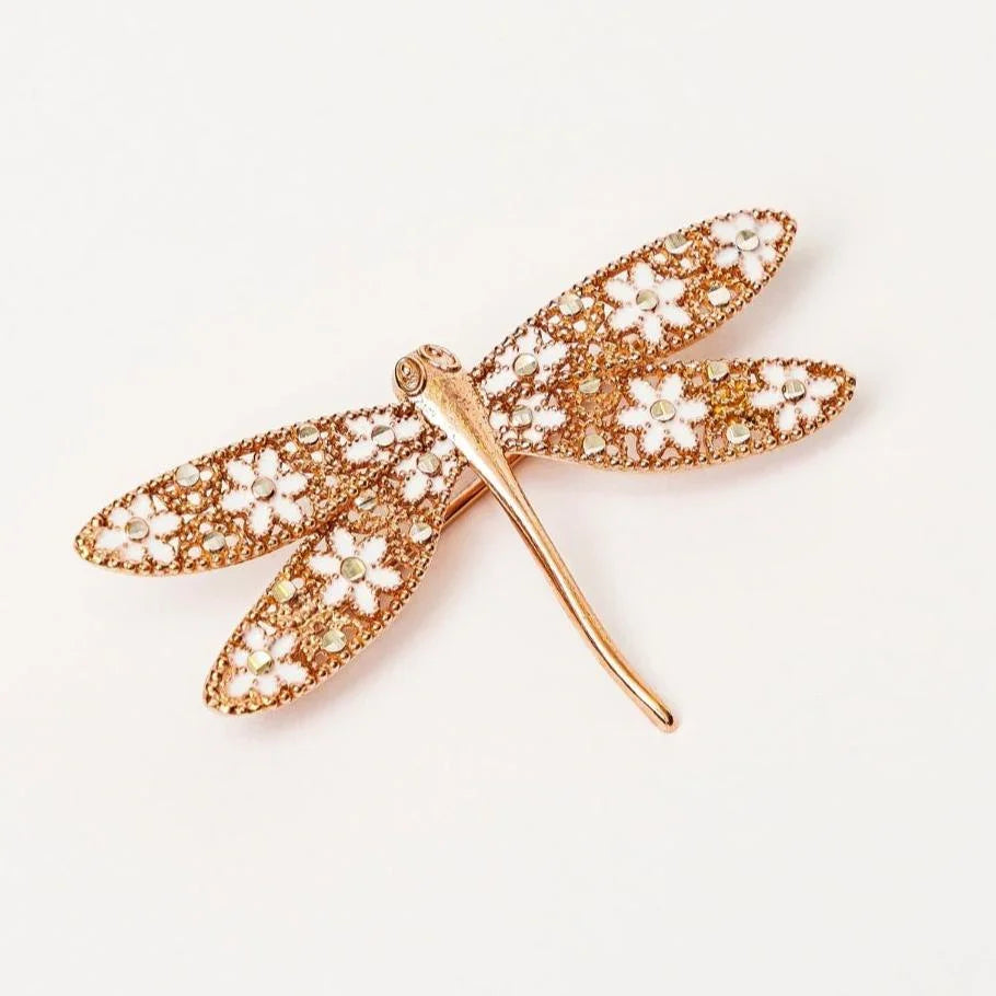 Gold dragonfly brooch with floral cutout wings and embedded rhinestones on white background