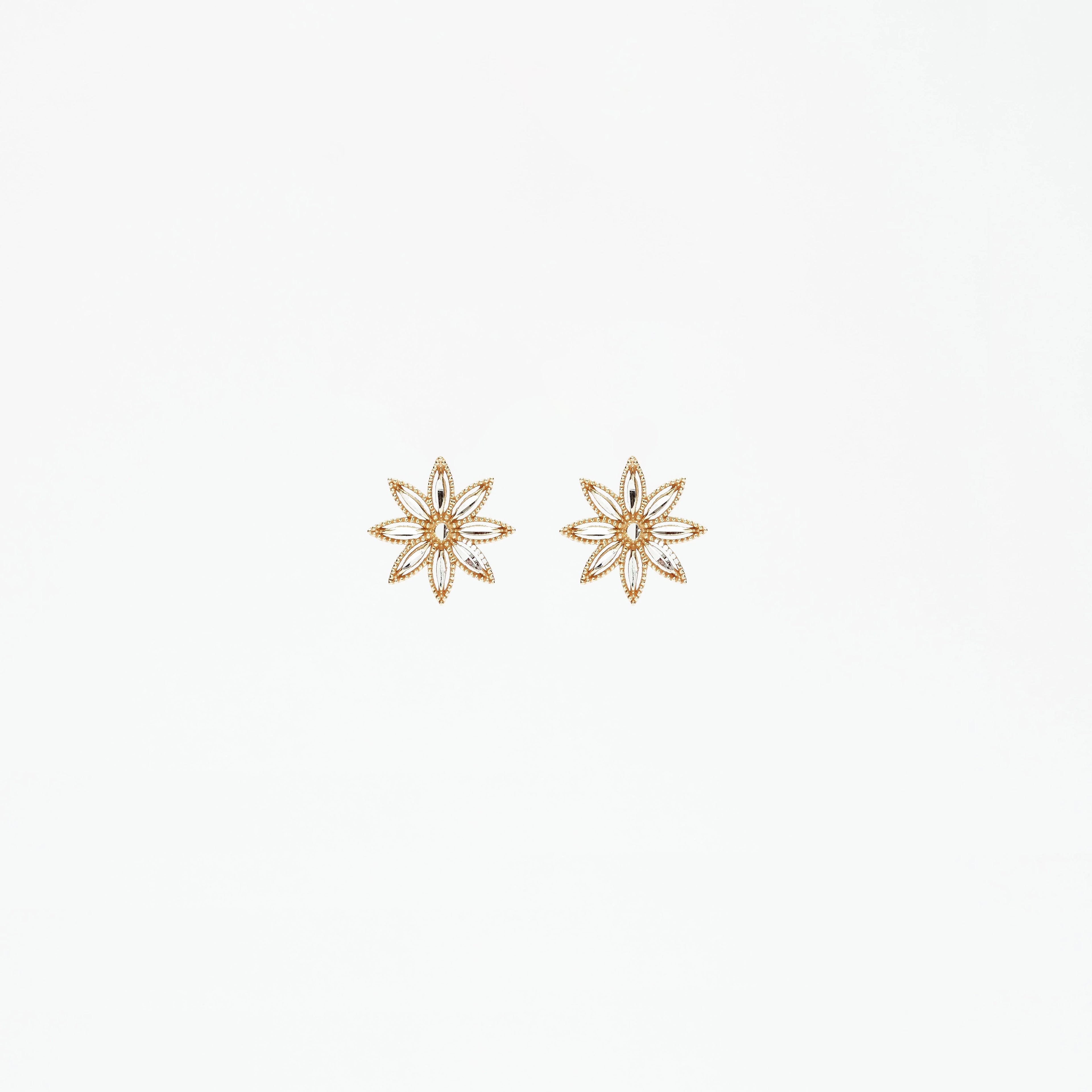 Pair of delicate gold and silver floral stud earrings on white background