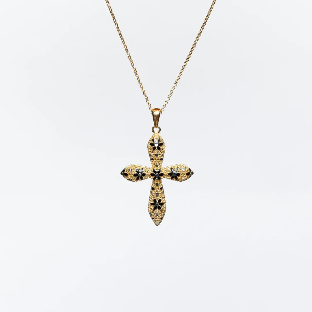 Gold cross pendant necklace with black and clear gemstone accents on white background