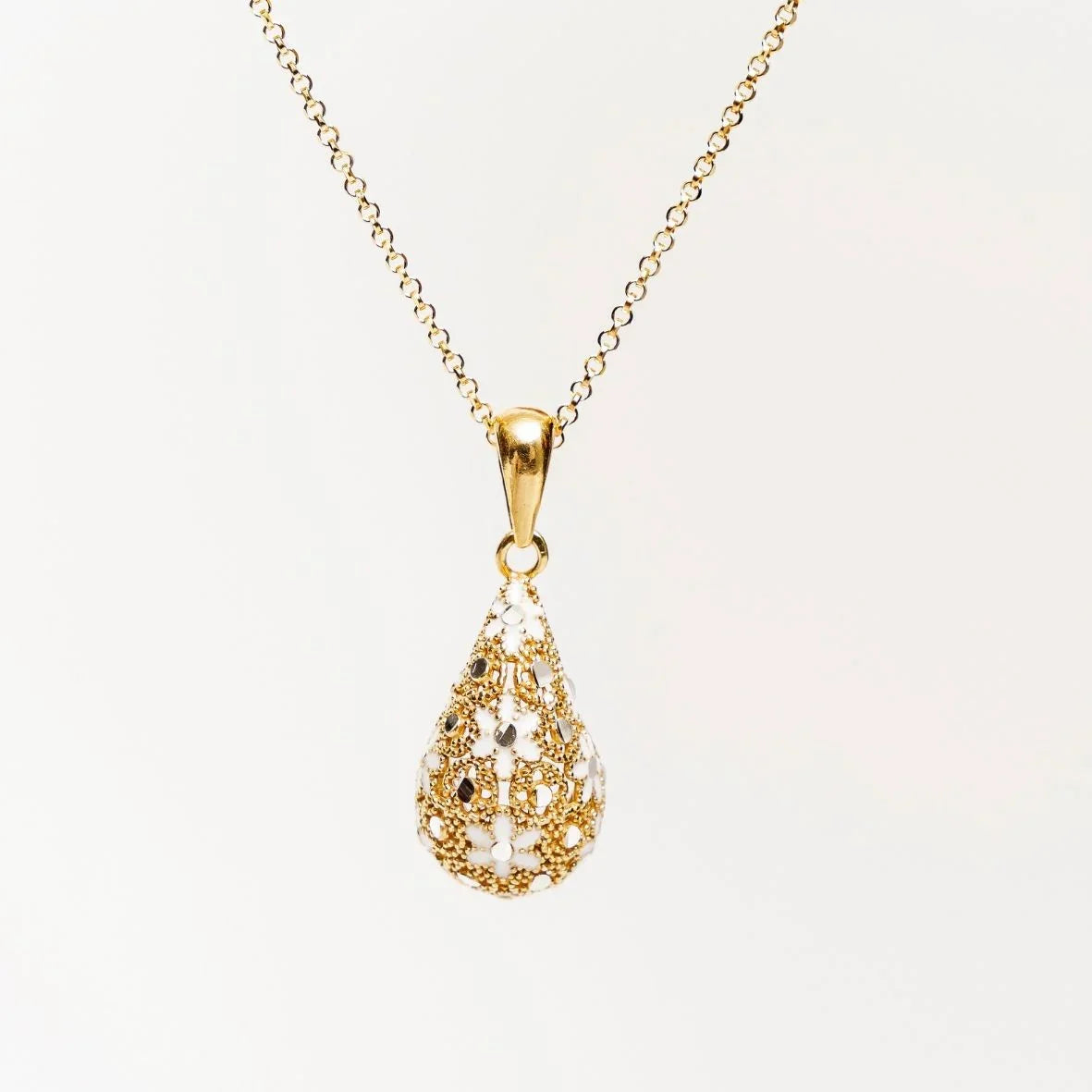 Gold teardrop pendant necklace with intricate filigree floral design on white background