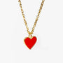 Gold chain necklace with a shiny red heart-shaped pendant on a white background