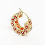 Gold hoop earring with red and white floral enamel design on white background