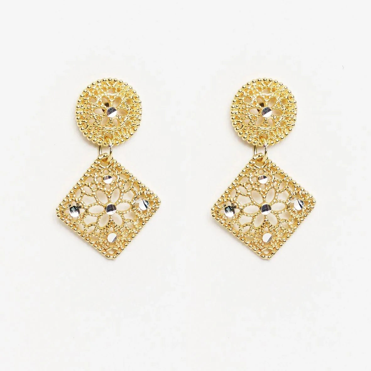 Pair of gold filigree dangle earrings with flower and bead accents on white background