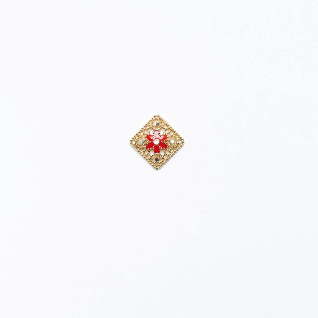 Golden diamond-shaped brooch with red flower and small gemstones on white background