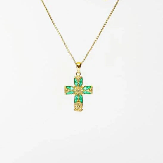 Gold cross pendant necklace with green gemstone inlays on a delicate chain