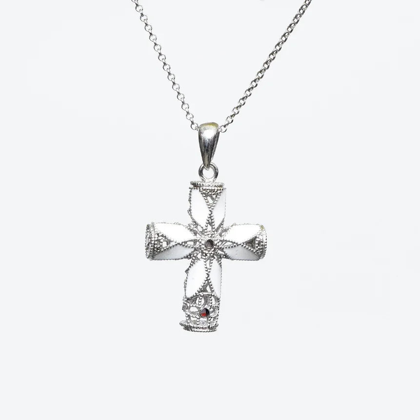 silver cross pendant necklace with intricate filigree and a small red gemstone on chain