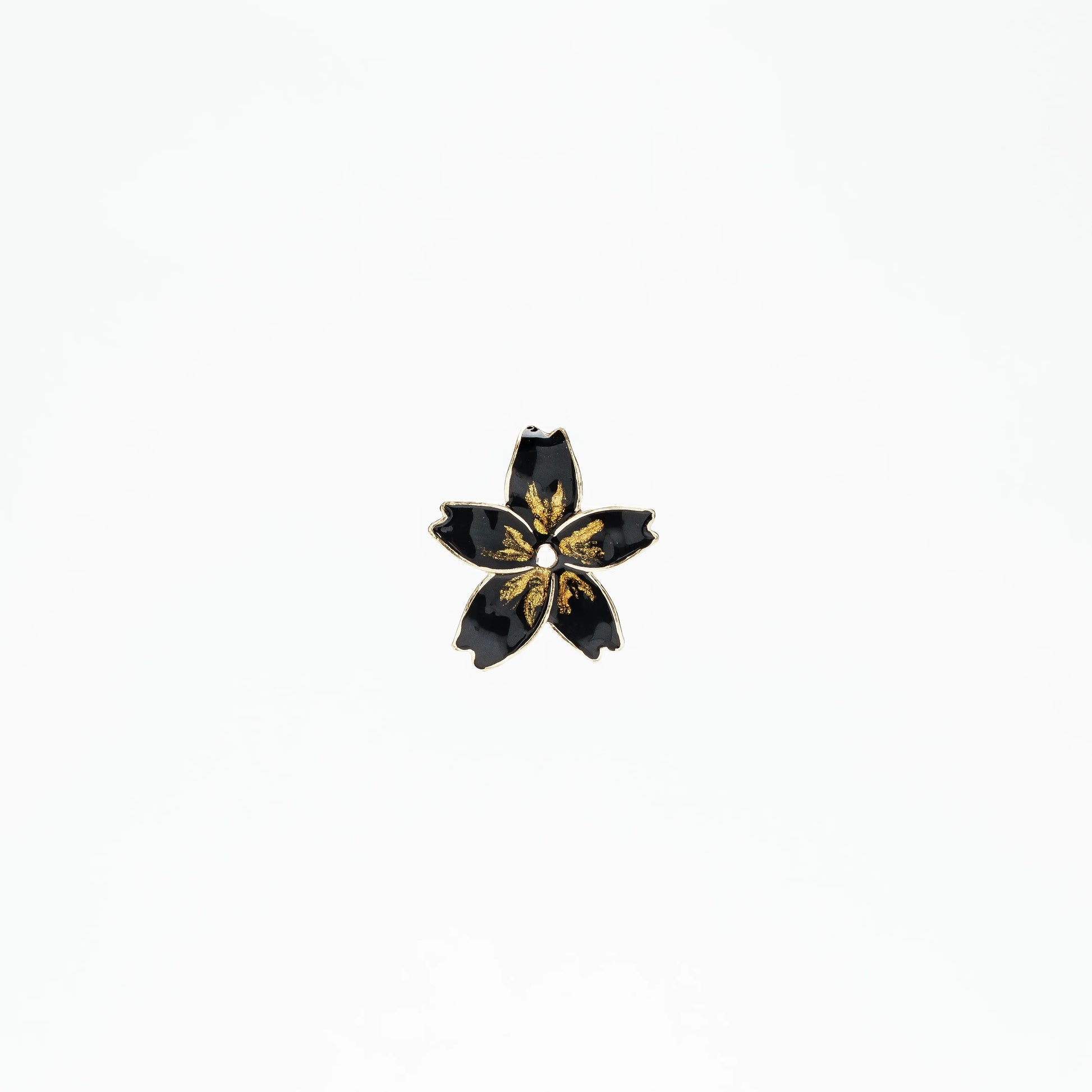 Black enamel flower pin with gold accents on white background