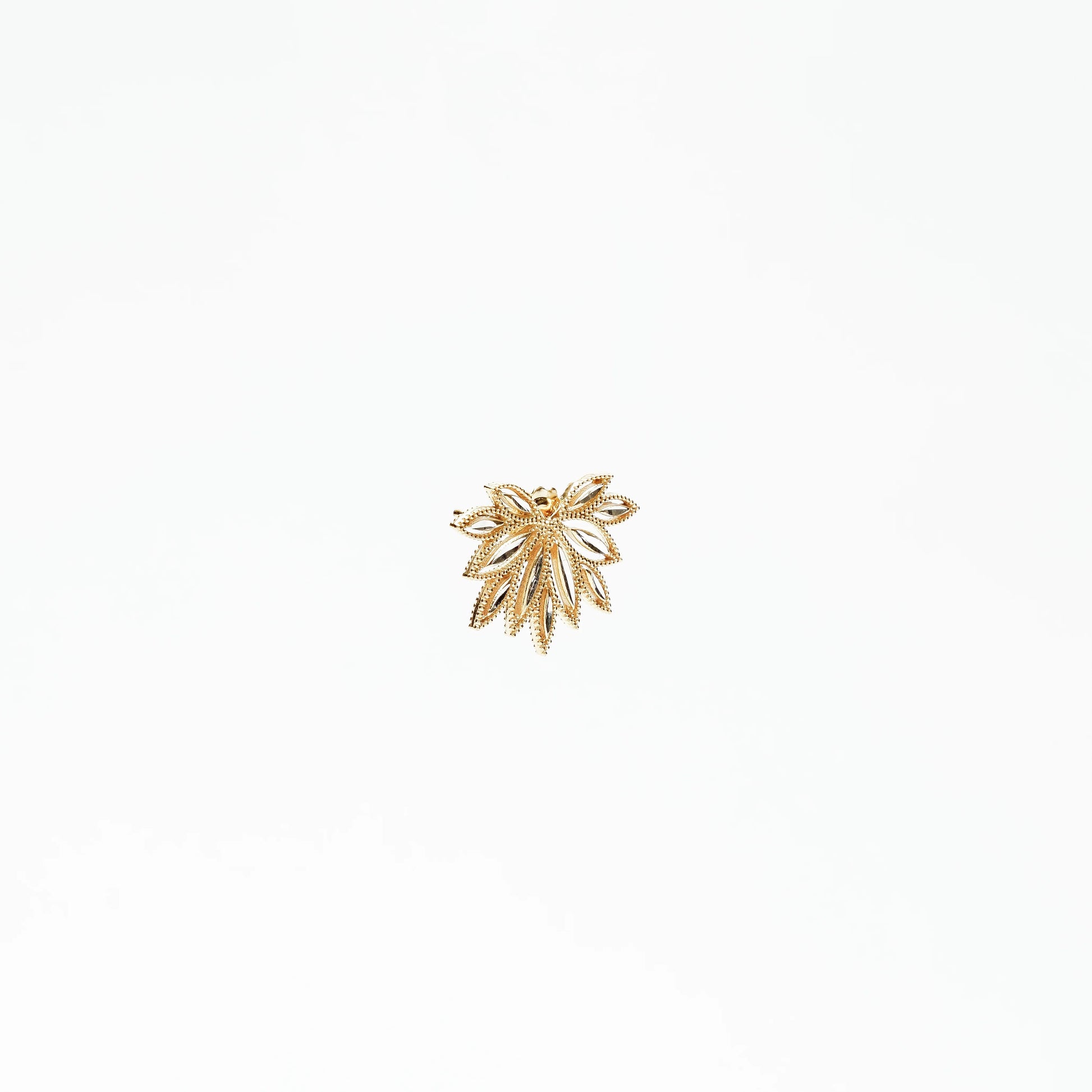 Gold leaf-shaped brooch with intricate cut-out and beaded details on white background