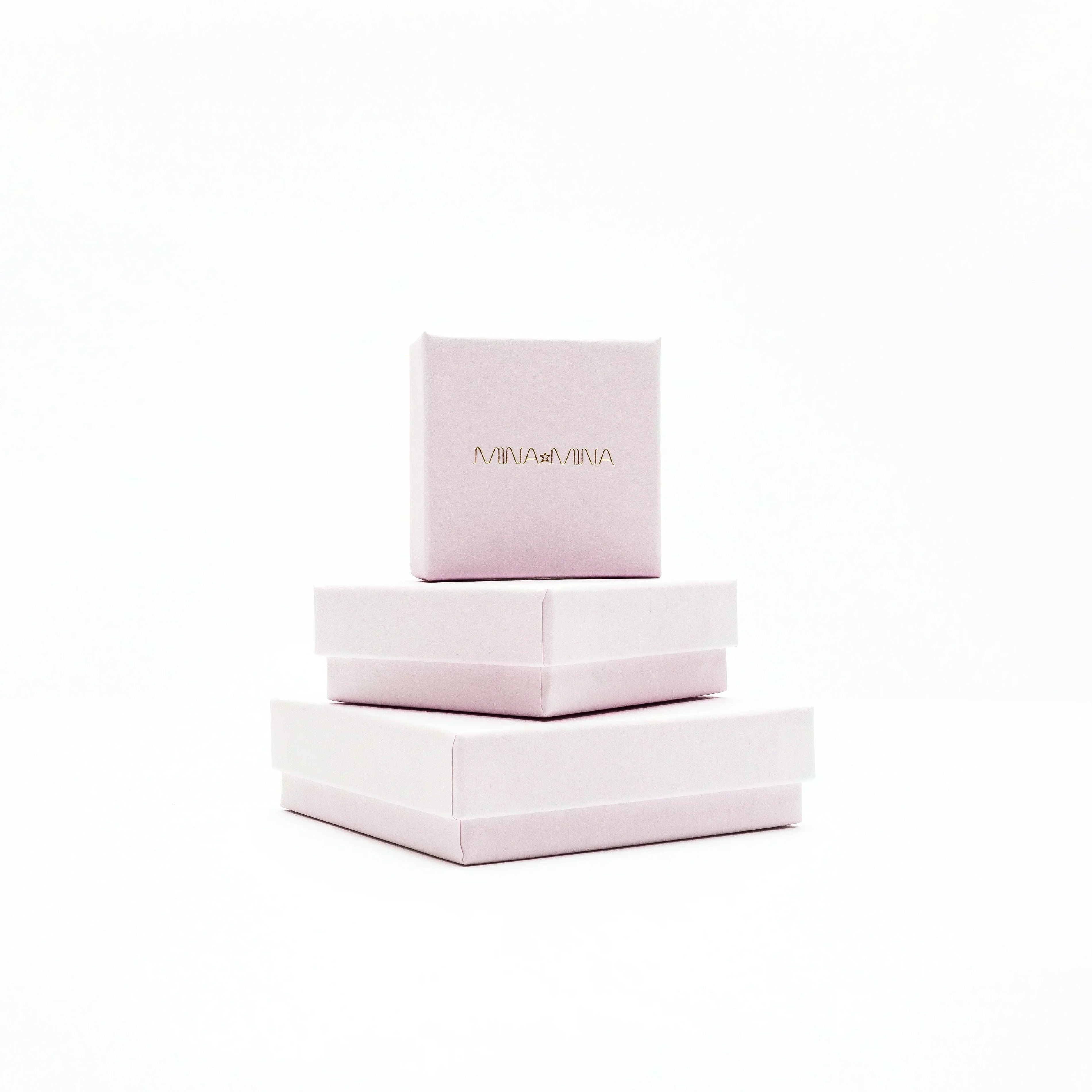 Stack of three pale pink gift boxes with gold MINA MINA logo on a white background