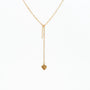 Elegant gold chain necklace with dangling bar and heart charm on white background