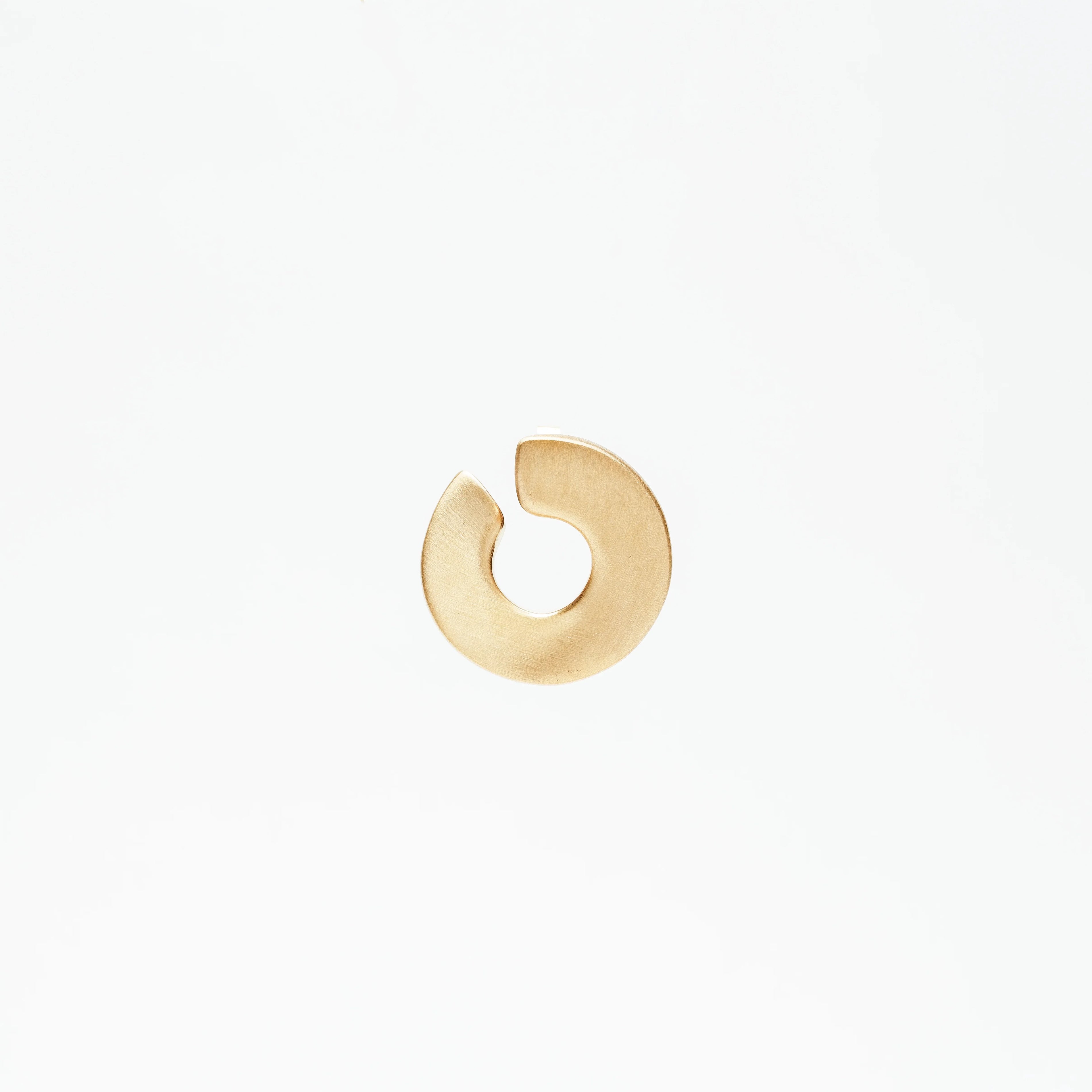Minimalist gold circular notch hoop earring on white background