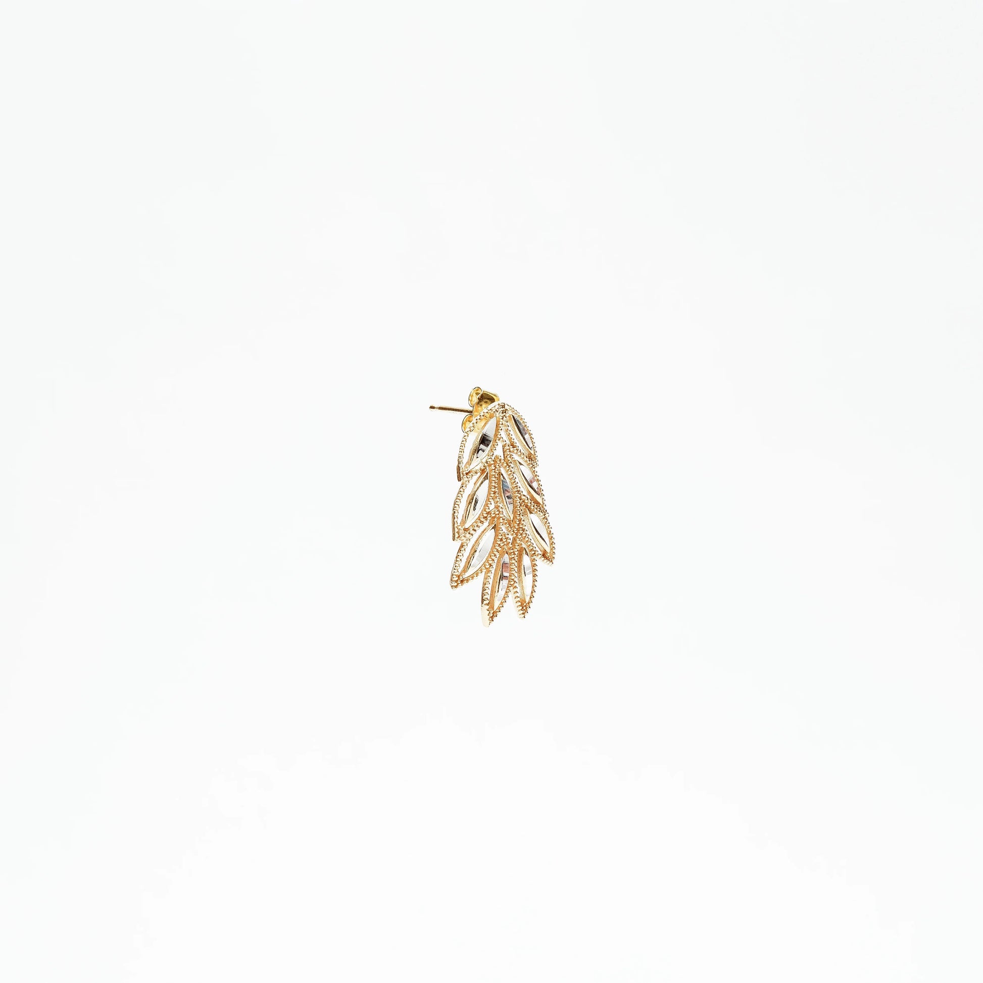Golden leaf-shaped drop earring with intricate cut-out details on white background