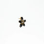 Black flower-shaped enamel stud earring with gold detailing and silver center on white background