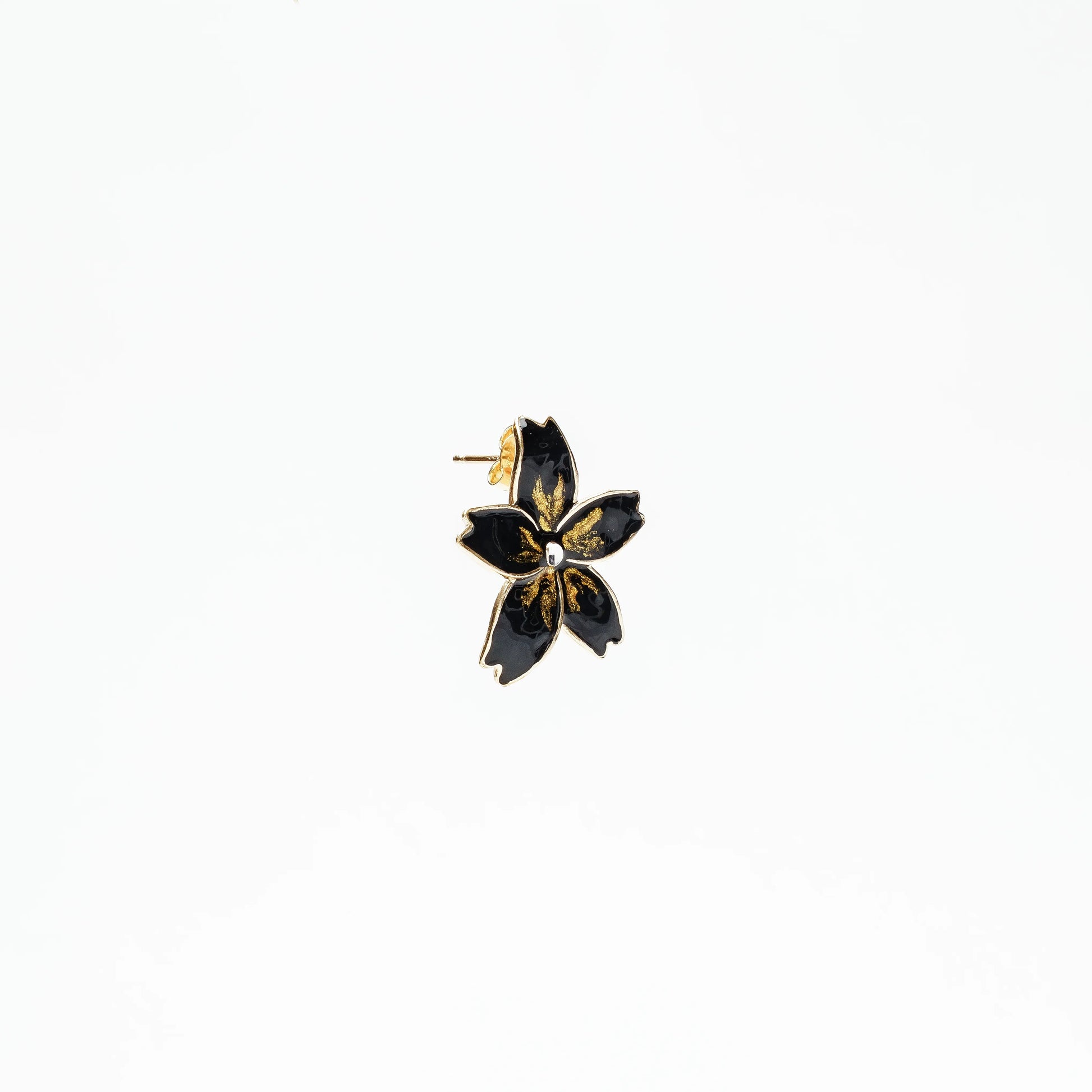 Black flower-shaped enamel stud earring with gold detailing and silver center on white background
