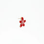Red flower-shaped enamel stud earring with gold edges on white background