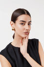 Portrait of woman with sleek hair wearing black sleeveless top and gold hoop earrings