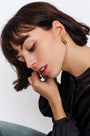 Close-up of woman with short brown hair wearing a gold chunky hoop earring and black blouse