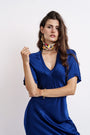 Woman in a royal blue satin dress with floral silk scarf and gold earrings and bracelet